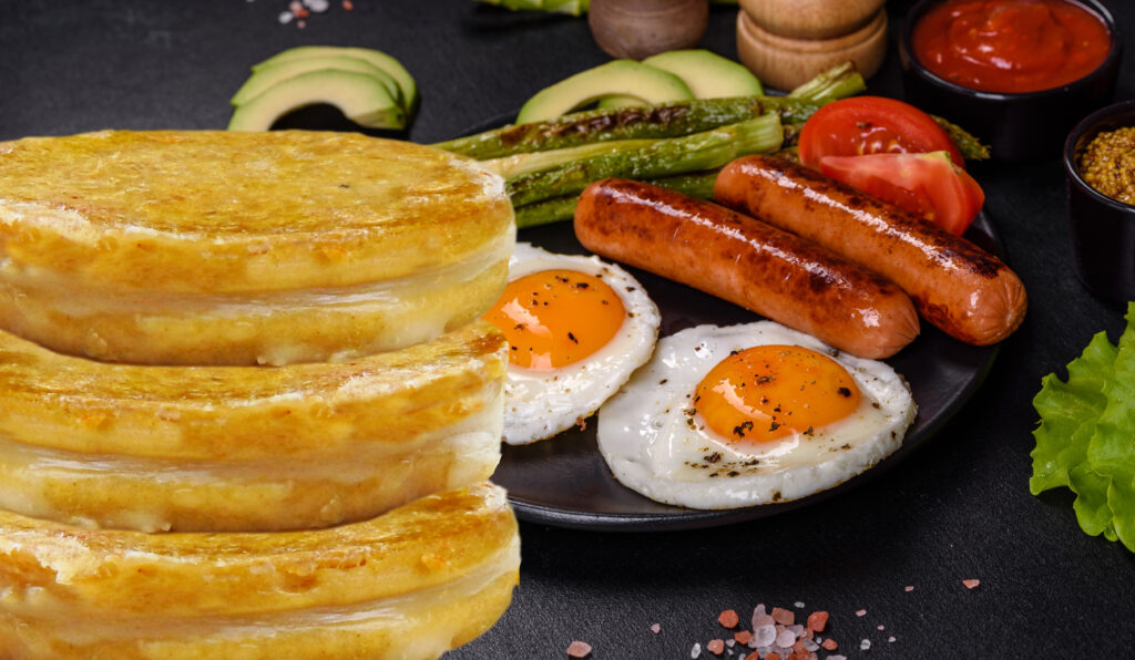 a delicious nourishing breakfast with fried eggs, sausages, asparagus, tomatoes, avocado, spices and herbs